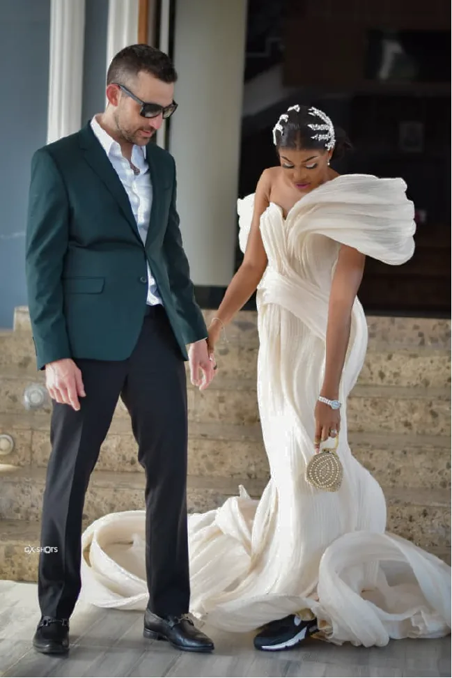 A couple in an emerald blazer and a sculptural cream gown