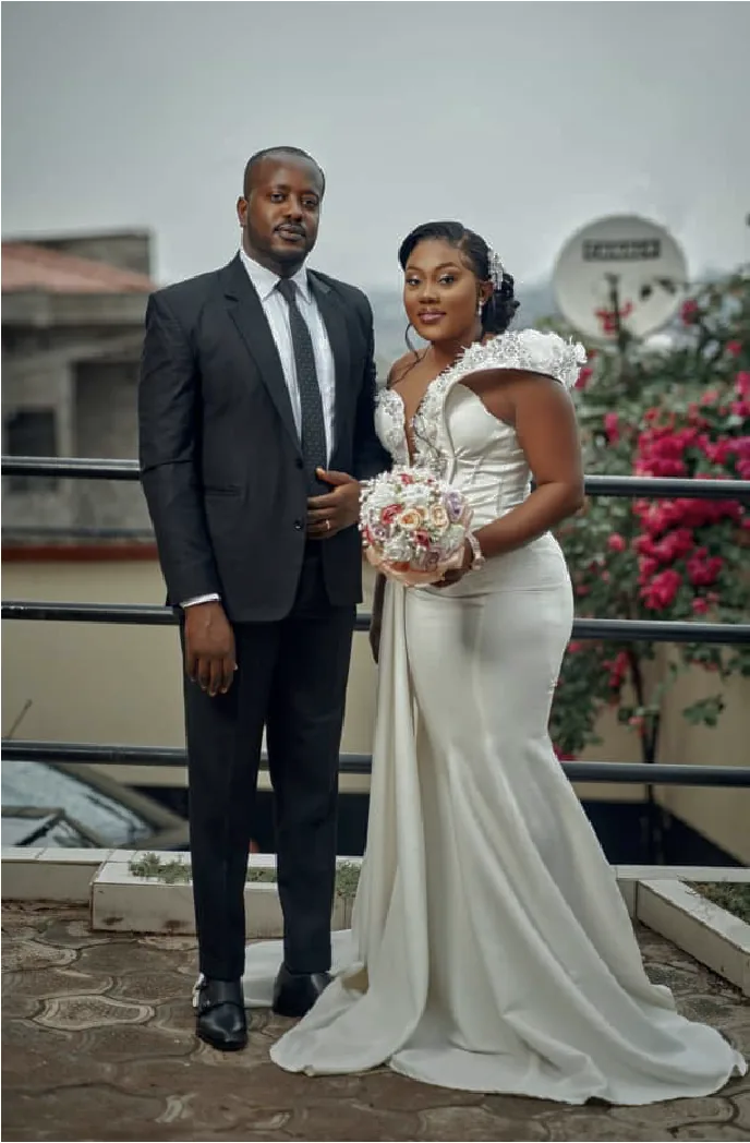 A bride in a white mermaid gown and a groom in black on a rooftop at dusk