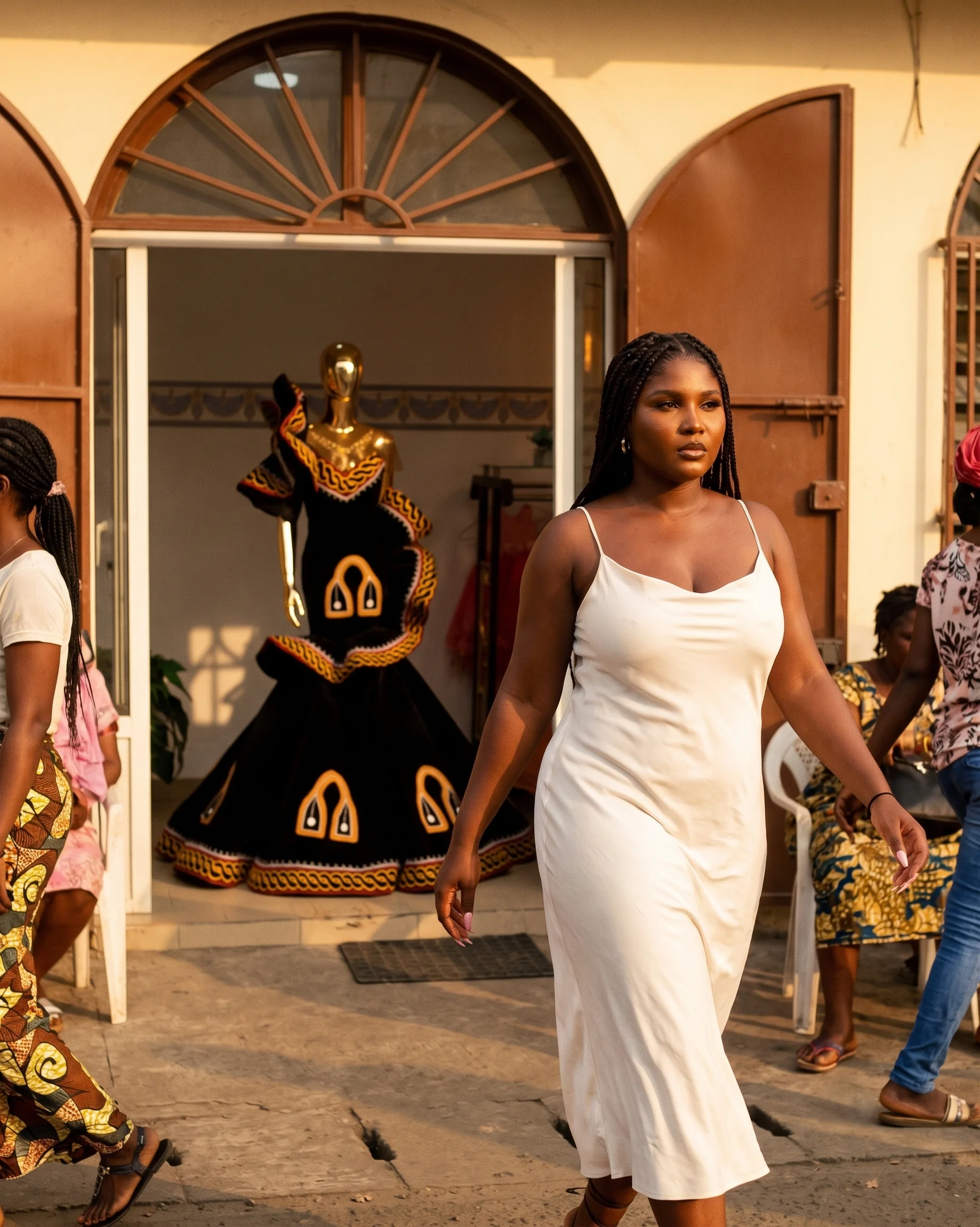 Model in a white slip dress walking through a sunlit arched courtyard